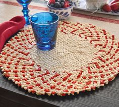 a placemat with red, white and blue designs sits on a table next to two glasses