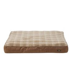 the dog bed is brown and tan with a checkered pattern on it's side