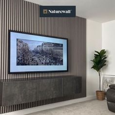 a large television mounted to the side of a wall in a living room next to a plant