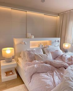 a white bed sitting in a bedroom next to a lamp on a night stand and a window