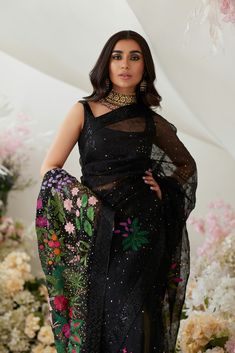 Indian Wedding Dress in Elegant Black Net Saree Style is a perfect balance of style and glamour. This stunning Indian Saree is beautifully adorned with embroidery, floral designs, and sitara, making it an epitome of beauty and your foremost priority to have a head-turning flawless wedding look. Embellished Blouse: The beautiful blouse in alluring black shade comes in sleeveless style. The blouse is heavily embellished with shimmering details and sequins. The elegant neckline and perfect stitching of this blouse make it a perfect choice to pair with the Embellished Saree. Black Saree: The Indian Saree in the net fabric is adorned with lavish details of hand-worked embellishments and floral designs. Threads, sequins, motifs, and embellished borders make this Indian Black Saree with Organza p Elegant Floral Embroidered Saree For Wedding, Elegant Floral Embroidery Saree For Wedding, Black Traditional Wear With Sheer Dupatta For Wedding, Floor-length Floral Embroidery Saree For Wedding, Black Organza Dress With Traditional Drape, Black Zari Work Wedding Gown, Floor-length Floral Embroidered Saree For Wedding, Black Dress With Sheer Dupatta For Wedding, Black Embroidered Fabric With Zari Work For Wedding