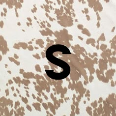 the letter s is written in black on a brown and white animal print fabric background