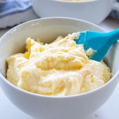 two bowls filled with mashed potatoes on top of a white counter next to a blue spoon