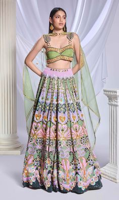 A green sequin-printed lehenga featuring pockets, adorned with gold chains, crystals, pearls and heart-shaped metal accents. It is paired with a green organza blouse, embroidered with gold chains, pearls, glass stones and beads, along with an asymmetrical organza dupatta with a pearl border and sequin scatter. Festive Embellished Green Sharara, Festive Green Embellished Sharara, Anarkali Embellished Green Choli, Green Embellished Anarkali Choli, Anarkali Style Embellished Green Choli, Embellished Green Lehenga For Festive Occasions, Festive Embellished Green Lehenga, Festive Green Embellished Lehenga, Green Silk Sets For Reception