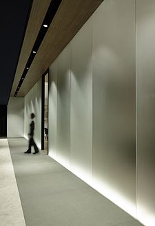 a man walking down a hallway next to a tall white building with lights on it