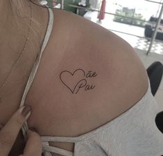 the back of a woman's shoulder with a small tattoo that says me pou