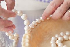 two hands are decorating a pie with pearls