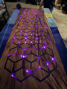 a wooden table with purple lights on it and a man standing next to the table