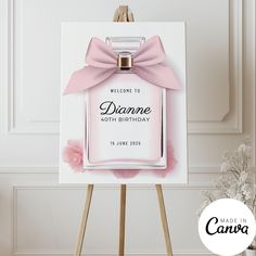 a pink perfume bottle with a bow on it sitting on top of a easel