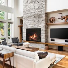 a living room with white furniture and a fire place in the fireplace, surrounded by large windows