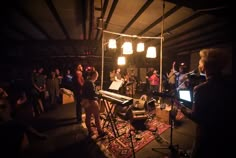 a group of people in a dark room with lights on and music equipment around them