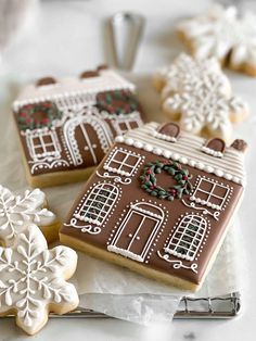 gingerbreads decorated with icing and decorations are sitting on a white tablecloth