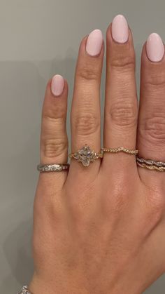 a woman's hand with three different rings on her fingers and one ring in the middle