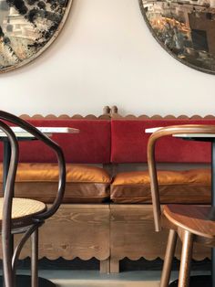 two chairs sitting next to each other in front of a wall with paintings on it