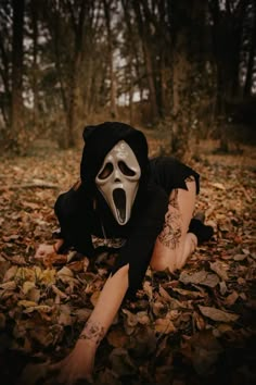 a person with a mask on laying in leaves