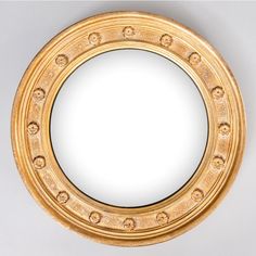 a gold circular mirror on a white wall