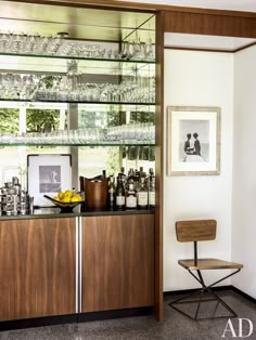 a room with a chair and shelves full of bottles, glasses and other items on it