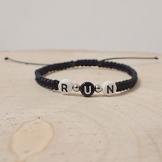 a black and white beaded bracelet with the word ron on it, sitting on top of a wooden table