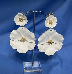 "This is a really pretty pair of white floral flower earrings.  The small flower at the top has the post for pierced ears.  The larger flower dangles from the smaller.  Each blossom has a gold center.  The length is 2 1/2\" and the width, 1 3/4\".    We are not sure what they are made of but they have the feel of soft leather.  They are in very good condition and are just perfect for the bride or summer occasion." White Dangle Flower Earrings For Spring, White Dangle Flower Earrings With Charm, White Dangle Flower Charm Earrings, White Wedding Jewelry For Spring, Spring Wedding White Jewelry, Spring Wedding Dangle Flower Earrings, Spring Wedding Flower Earrings For Pierced Ears, Elegant White Flower Pendant Earrings, White Dangle Flower Earrings