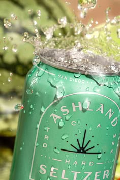 a close up of a can of soda with water splashing off the top and bottom