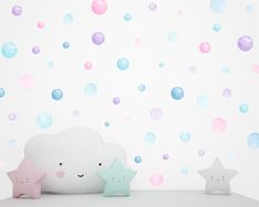 two stars and a cloud are next to each other on a shelf in front of a wall with bubbles