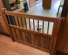 a small white dog standing on top of a wooden stair case next to a kitchen