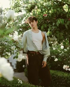 a young man standing in front of some flowers