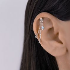 a woman's ear is adorned with chain and crystal beads, which are hanging from the back of her ear