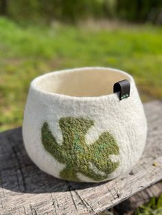 a white and green bowl sitting on top of a wooden table next to a grass covered field