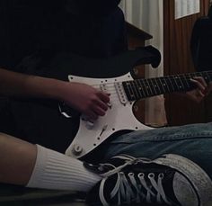 a person sitting on the floor playing an electric guitar