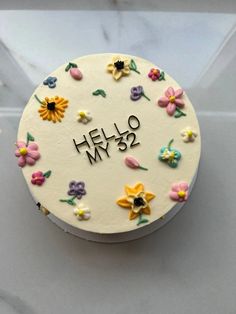 a white cake with flowers and the words hello may on it