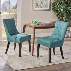 two blue chairs sitting in front of a wooden table