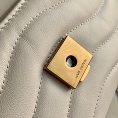 a close up of a white purse with a gold button on it's side