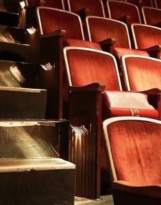 rows of red chairs in an auditorium with wooden steps leading up to the second floor