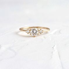 a gold engagement ring with three diamonds on the top and bottom, sitting on a white surface