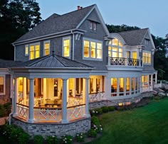 a large house lit up at night with lights on the front porch and covered patio