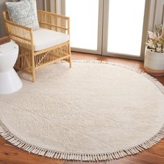 a white rug with fringes on the floor next to a chair and toilet in a room