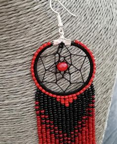 a red and black beaded dream catcher hanging from a silver necklace on a mannequin