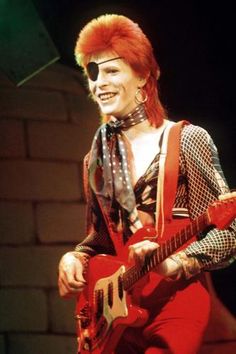 a woman with red hair playing an electric guitar