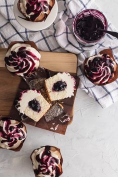 some cupcakes are sitting on a cutting board with blueberries and cream frosting