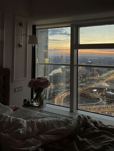 a bedroom with a large window looking out at the city lights from it's bed