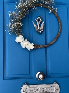 a blue door with a metal post and white flowers on the handle, next to a wreath