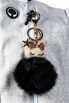 a close up of a key chain on a person's silver jacket with a black pom - pom