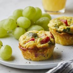 two muffins on a plate with grapes and orange juice