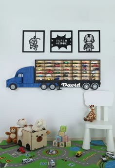 there is a toy truck on the wall with pictures above it and toys in front of it