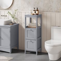 a white toilet sitting next to a sink and a gray cabinet in a bathroom under a mirror