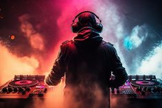 a dj in headphones standing next to his turntables and mixing equipment at a concert