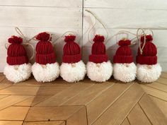 six red and white knitted santa hats with pom - poms on them