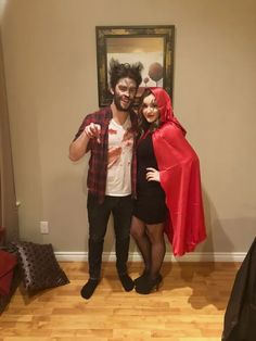 a man and woman dressed up in costumes posing for a photo with a painting on the wall behind them