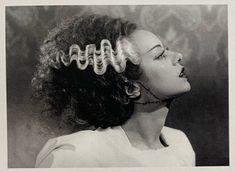 a black and white photo of a woman with curly hair in an old fashion hairstyle